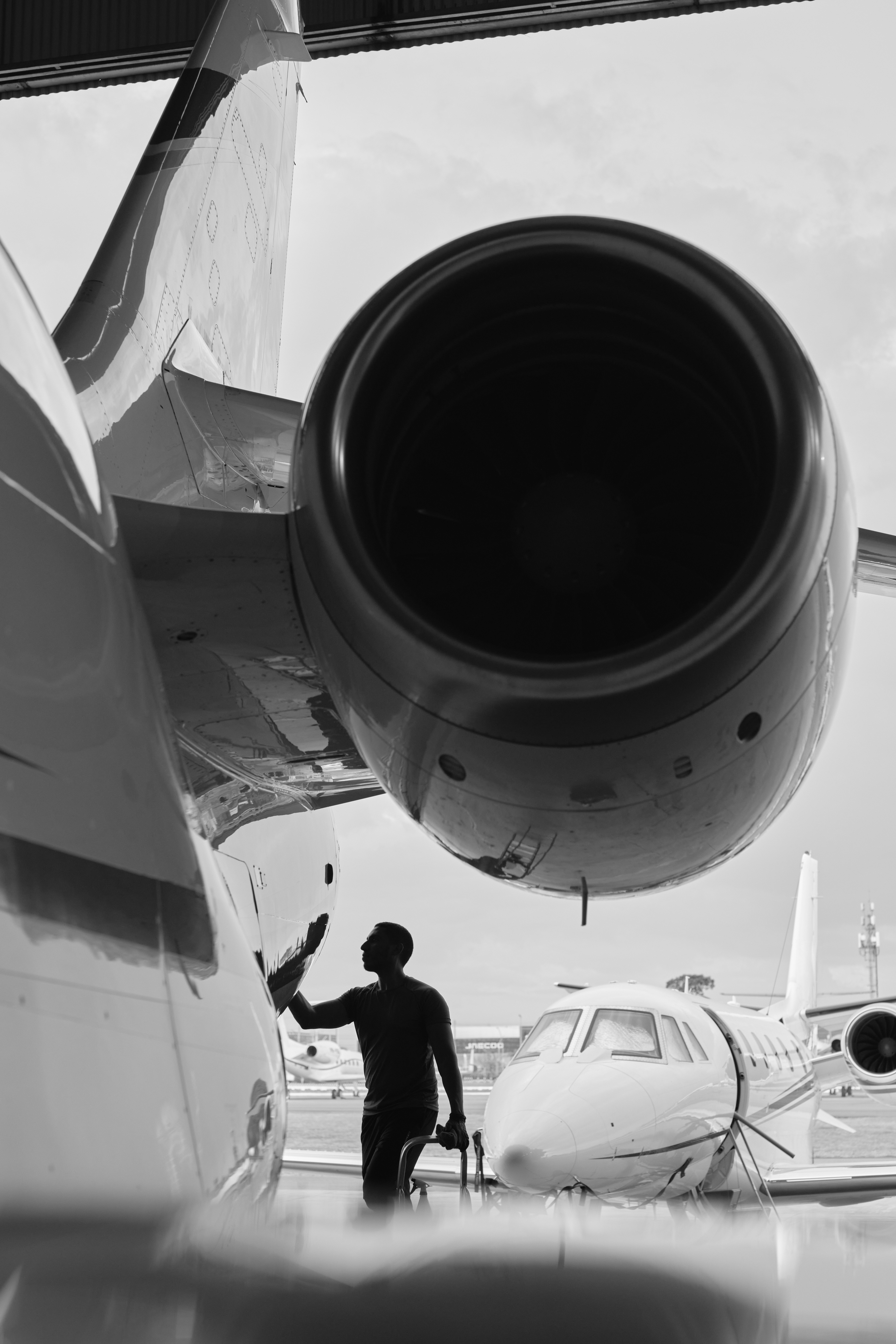 Profissional cuidando de uma aeronave executiva no hangar, em fotografia em preto e branco